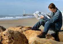 Kille läser på stranden