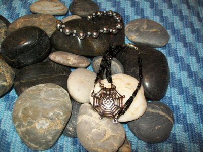 Övre: Svart vaxad bomullstråd med silverpärlor och "seedbeads". Nedre: Svart smyckesvajer med "seedbeads" och spindel